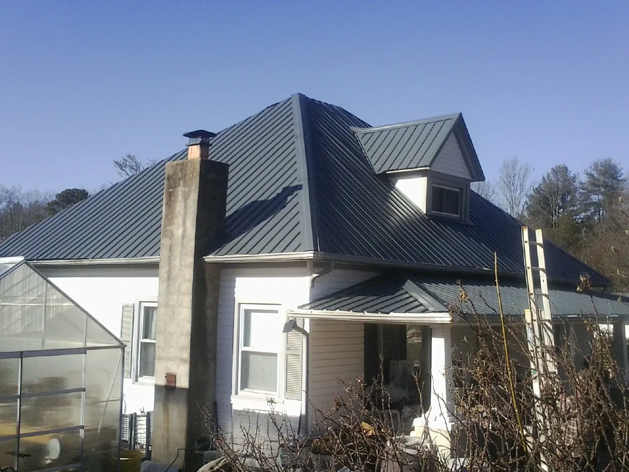 Dark blue standing seam metal roof on a white farmhouse with dormer — Slate & Tile Roof Repair by Roofing Brothers in Delmar