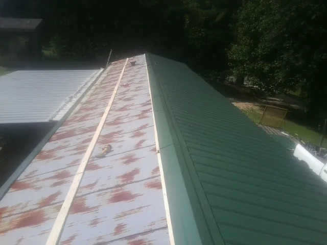Old rusted panels beside newly installed green metal roofing — Wind Damage Roof Repair by Roofing Brothers in Delmar