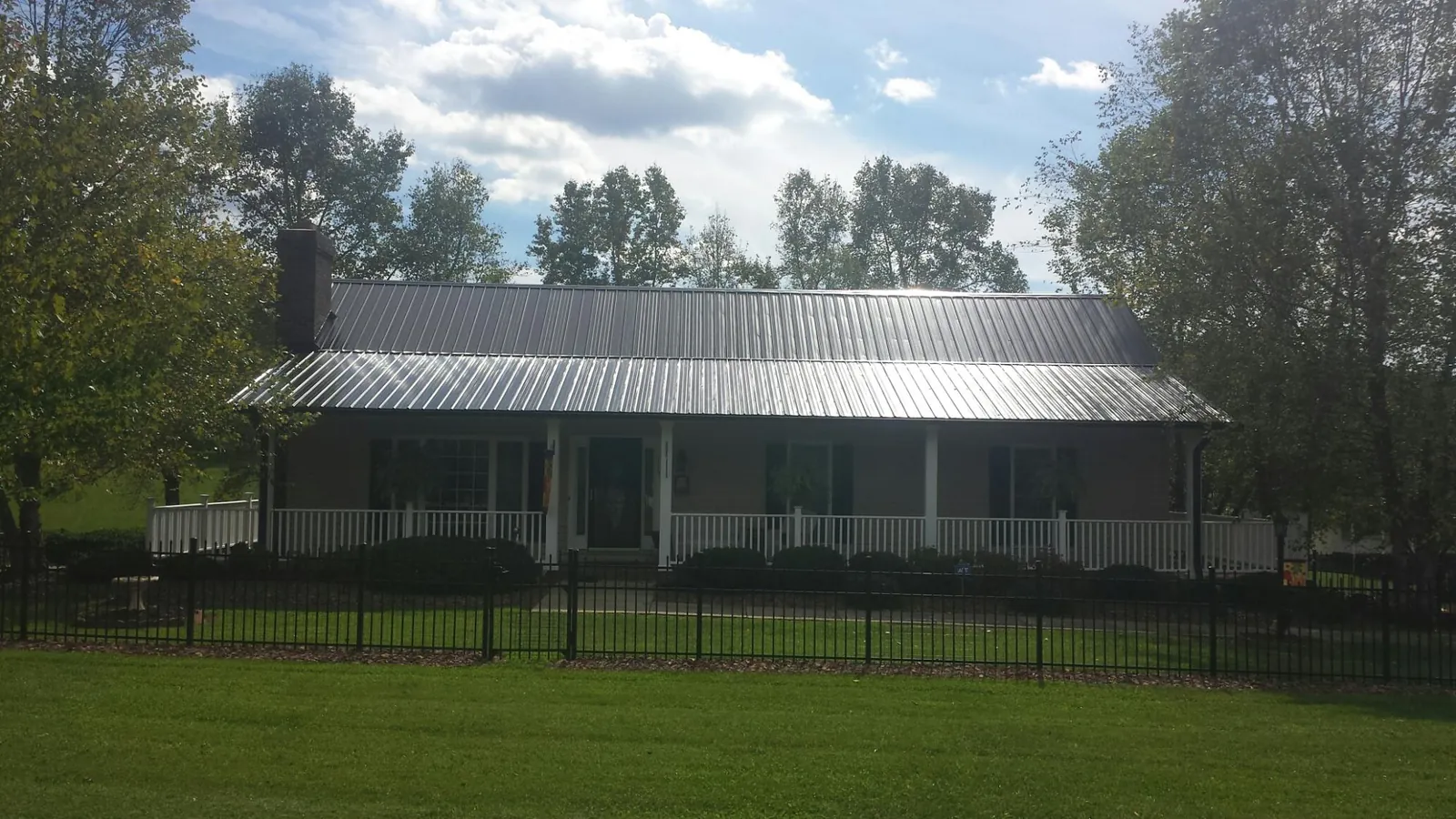 Gray metal roof on a brick ranch with a full width front porch — Gutter Guard Installation work by our crew in Delmar