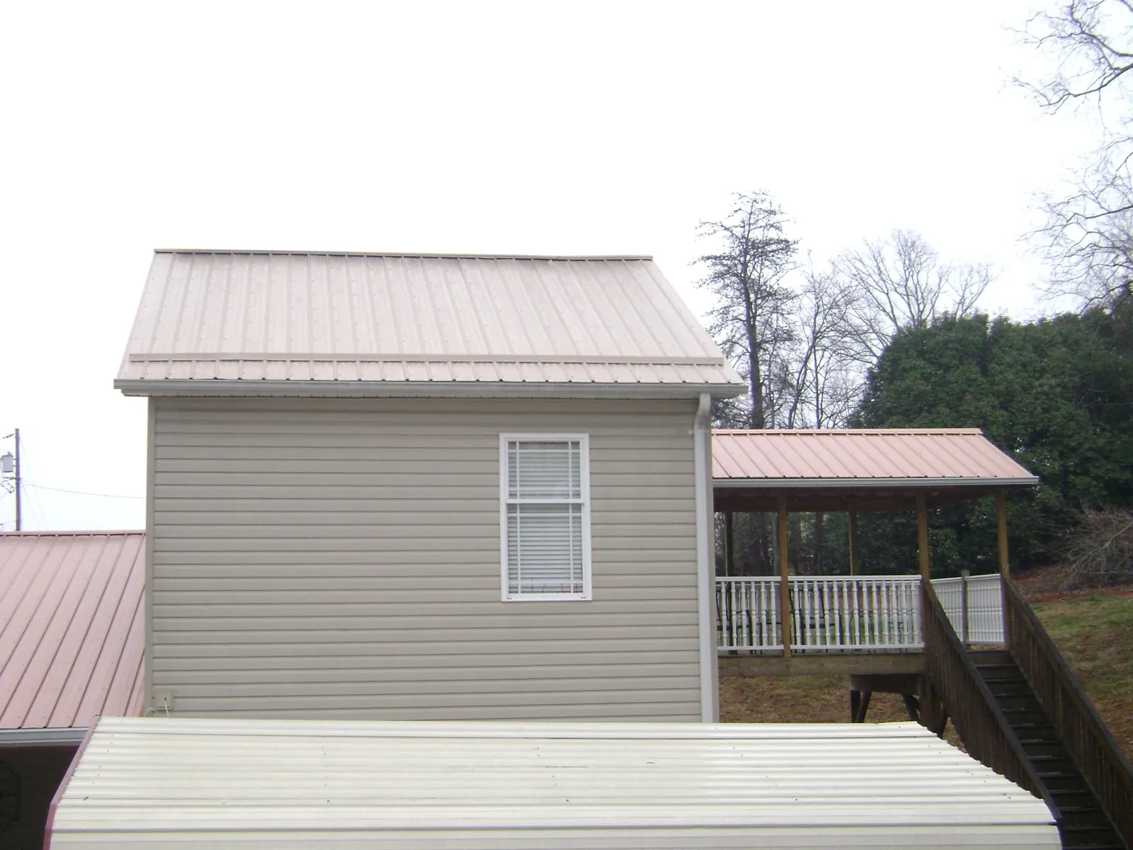 Tan metal roofs on a two story addition and attached porch, from a Roof Replacement job in Delmar